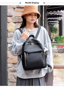 Outdoor lifestyle shot of a black nylon backpack with gold zippers shown on a model