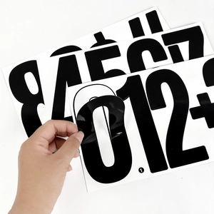 Detail of peeling a 6-inch black vinyl number sticker showing adhesive quality and thickness