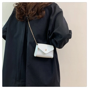 Detail of light blue faux crocodile skin texture and gold chain on square crossbody bag