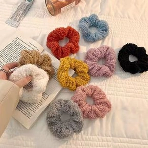 Soft faux fur scrunchies shown in nine colors on a white bedding lifestyle scene