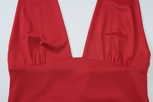 Détail d'un haut rouge à col en V profond montrant les fronces et la maille extensible