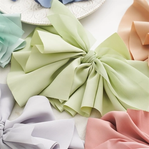 Detailed view of large fabric bow hair clips in soft Morandi pastel colors like green and lilac
