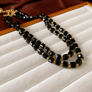 Detailed macro view of black faceted crystal beads and gold spacers on jewelry tray