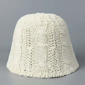 Gros plan du chapeau bob en tricot blanc cassé montrant le détail du motif de torsades
