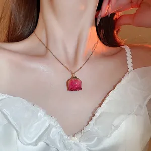 Elegant gold necklace set with a real preserved pink rose petal pendant worn by a model