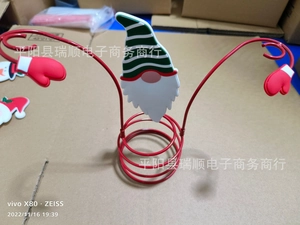 Close-up of Christmas wine bottle holder with festive gnome and red metal spiral base