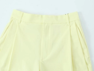 Detailed view of pale yellow wide-leg trousers showing waistband and zipper craftsmanship