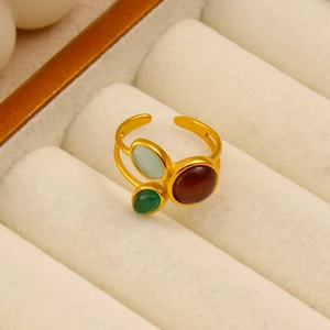 Détail de la bague ajustable dorée avec trois pierres de couleur sur velours blanc