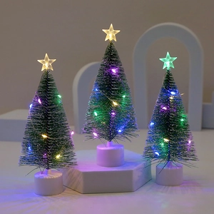 Close-up of mini glowing Christmas trees with LED string lights and star tree toppers