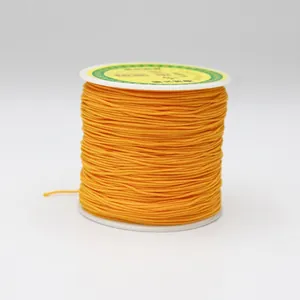 Detailed view of bright yellow 0.8mm nylon cord for jewelry making on a white spool