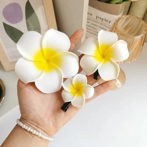 Detailansicht von drei weißen und gelben Frangipani-Haarspangen in verschiedenen Größen