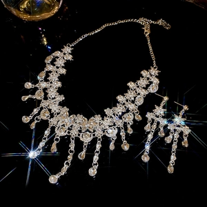 Gros plan du collier fleur en strass étincelants et boucles d'oreilles à pompons