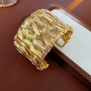 Detail of vintage golden twisted weave open cuff bracelet on elegant wooden display
