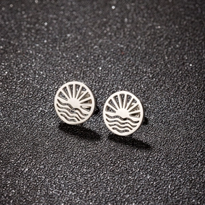 Detailed macro view of silver geometric stud earrings with hollow sun and wave patterns