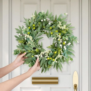Detailed close-up of artificial olive leaf wreath with white berries on a white front door