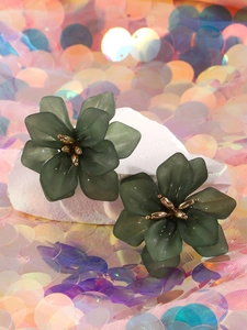 Close-up of matte dark green acrylic flower earrings with gold stamens on stone