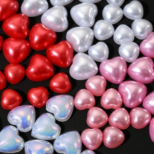 Macro shot of 3D heart-shaped pearl beads in red, pink, and white for nail art design