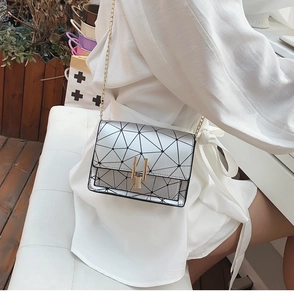 Detail shot of a silver geometric shoulder bag featuring triangular panels and gold hardware