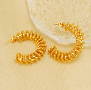 Detailed close-up of golden spiral hoop earrings with a textured spring-like design