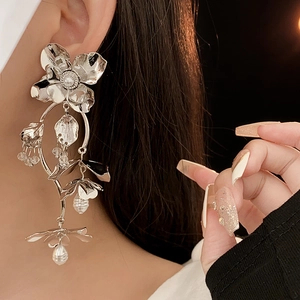 Detailed view of silver flower earrings with pearl pendants and beaded tassels on model