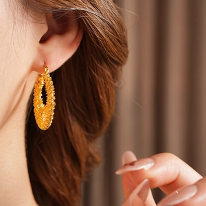 Gros plan de boucles d'oreilles tressées plaquées or portées par un mannequin