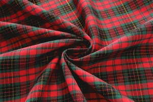 Detailed view of red and green plaid fabric with golden glitter and soft texture