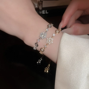 Macro detail of snowflake pendant bracelets in gold and silver finish with pavé crystals