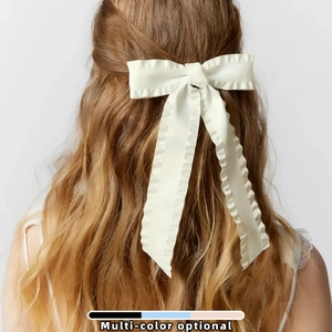 Elegant white ruffle bow hair clip with ribbons for women shown on a model's hair
