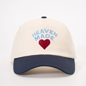 Detail view of the HEAVEN MADE blue text and red heart embroidery on the white crown