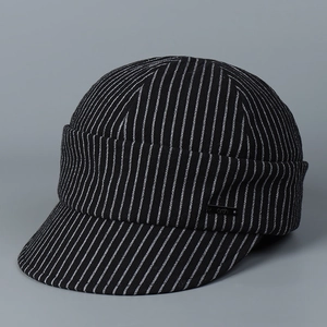 Detailed close-up of a pinstripe baker boy hat with a small metal logo plaque
