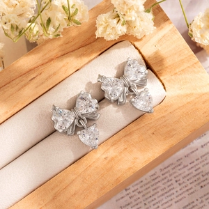 Silver bow heart drop earrings with clear zircon crystals on a jewelry box display