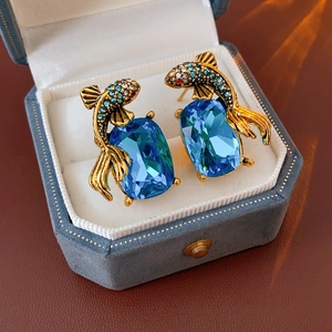 Detail of vintage koi fish earrings with blue gemstone in a blue velvet jewelry box
