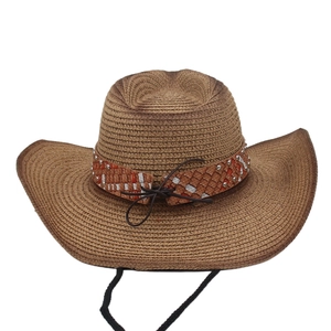 Detail of bohemian straw cowboy hat featuring metallic studs and a woven decorative band
