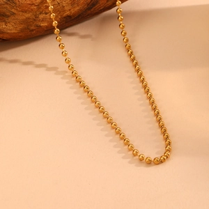 Close-up of a gold-plated stainless steel bead chain necklace displayed on natural wood