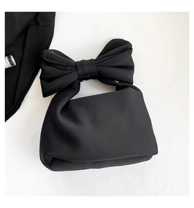 Detail of minimalist black nylon puffer bag featuring a large decorative bow handle