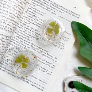 Detail of round and heart-shaped phone grips with real four-leaf clovers and gold foil