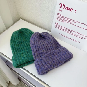 Detail of green and purple chunky knit beanies featuring wide rolled edges and ribbed texture