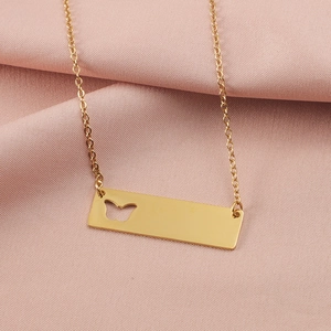 Macro detail of gold vertical bar necklace featuring a hollowed butterfly cutout on pink fabric