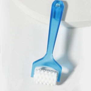 Close-up of handheld sky blue facial roller massager on white stone display stand