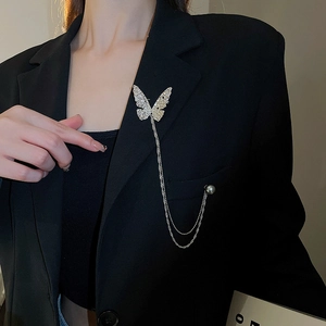Detail of silver butterfly brooch with rhinestones and pearl tassels on a black blazer