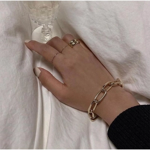 Close-up of chunky gold link bracelet and ring set worn on hand in a stylish setting