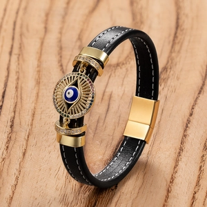 Dettaglio del bracciale in pelle nera intrecciata con ciondolo occhio greco dorato