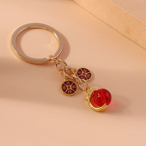 Detailed close-up of a gold Chinese style keychain with red bead and lucky charms