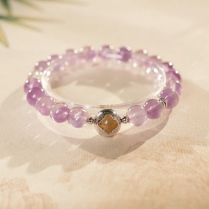 Detailed macro view of purple amethyst beads and silver hollow clover charm on bracelet