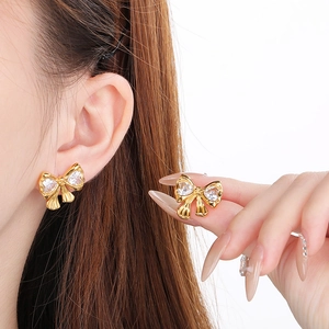 Close-up of 18K gold butterfly stud earrings with sparkling white zircons on a model