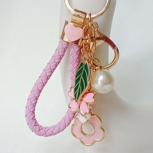 Detail of pink floral keychain with braided leather strap, cherry blossom and heart charm