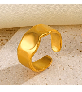 Detailed view of wide irregular hammered gold ring on beige travertine stone