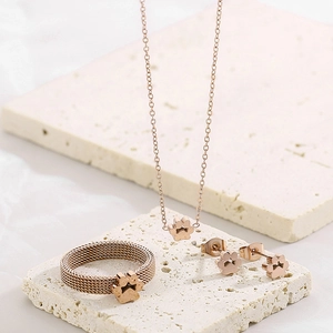 Rose gold jewelry set with mesh ring and cat paw pendants on beige stone tiles