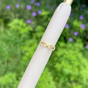 Detailed close-up of a 18K gold plated bow-shaped ring with zircons on a white display stand
