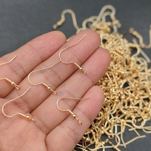 Primer plano de ganchos para pendientes dorados con bola y resorte para joyería DIY